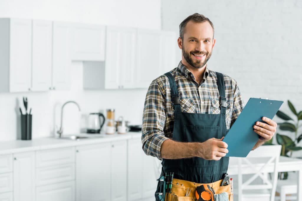plumber holding clipboard in kitchen